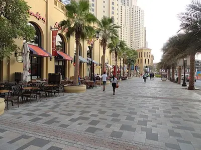 a city street with tables and chairs and palm trees at Chic waterfront 1 bedroom apartment, walk to beach, promenade, metro in Dubai