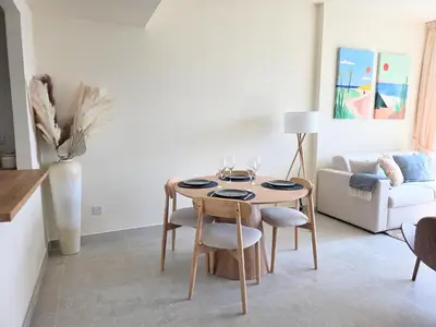 a living room with a table and chairs and a couch at Chic waterfront 1 bedroom apartment, walk to beach, promenade, metro in Dubai