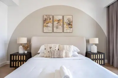 a bedroom with a white bed with three paintings on the wall at GuestReady - Lux Apt Downtown | Near Dubai Mall in Dubai