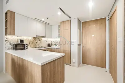 a kitchen with a white counter and wooden cabinets at High-Floor 1BR Facing the Marina and City, Minutes from Marina Beach with Easy Access to Marine Transport, LIV Marina, Dubai Marina by Deluxe Holiday Homes in Dubai