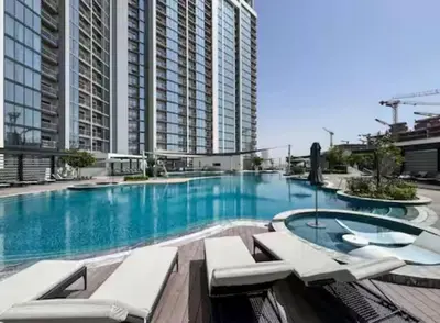 a large swimming pool with white chairs and buildings at Spacious apartment with Burj Khalifa view close to Dubai mall! in Dubai
