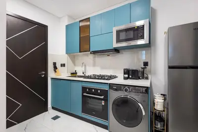 a kitchen with blue cabinets and a washing machine at Opalz by Danube,Dubai Science Park - Studio Apartment - Allsopp & Allsopp in Dubai