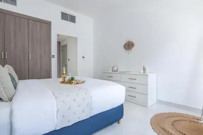 a white bedroom with a large bed with a tray on it at Frank Porter - Polo Residence C5 in Dubai