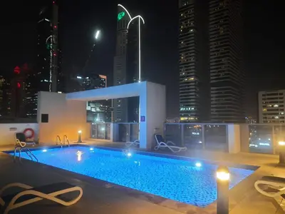 a swimming pool on the roof of a building at night at Luxury Apartment Fully Furnished Jumeirah Garden City in Dubai