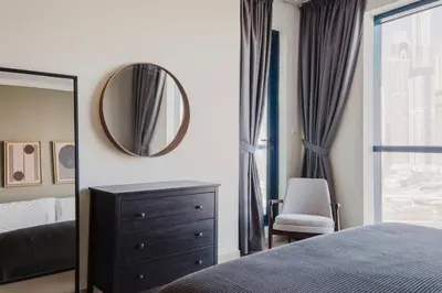a bedroom with a mirror and a dresser and a chair at Blueground JLT pool gym nr Marina JBR DXB-1616 in Dubai