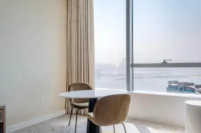 a table and chairs in a room with a large window at Blueground The Palm Jumeirah pool nr Atlantis DXB-1722 in Dubai