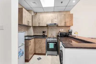 a kitchen with wooden cabinets and a stove at StayShort - Chic Studio Apartment in JVC Sleeps 4 in Dubai