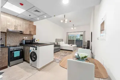 a kitchen and living room with a table and a dining room at StayShort - Chic Studio Apartment in JVC Sleeps 4 in Dubai