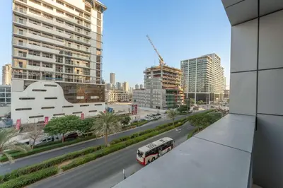 a bus driving down a city street with tall buildings at StayShort - Chic Studio Apartment in JVC Sleeps 4 in Dubai