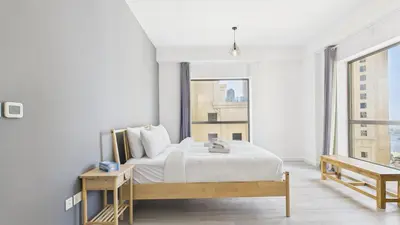 a white bedroom with a bed and a large window at Spacious 2 BR with Sea and Marina View Bahar JBR in Dubai