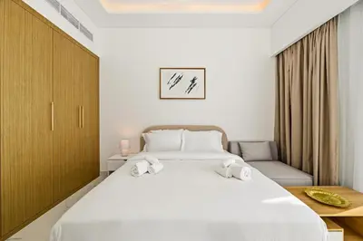 a bedroom with a large white bed with two towels at Estudio Amira en Dubai by beBalmy in Dubai