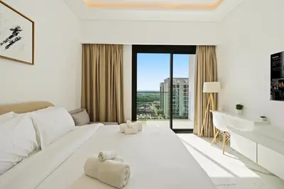 a white bedroom with a large white bed and a desk at Estudio Amira en Dubai by beBalmy in Dubai