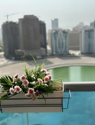 a bouquet of flowers sitting on a table next to a pool at Helena - spacious studio with canal view and big Balcony in Dubai
