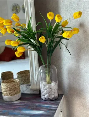 a glass vase with yellow flowers and white rocks at Helena - spacious studio with canal view and big Balcony in Dubai
