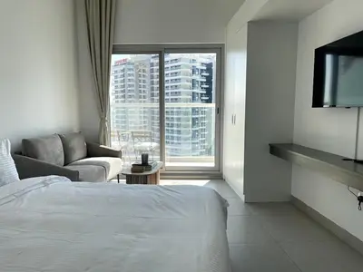 a bedroom with a bed and a couch and a window at Stunning New Studio - Near Dubai Hills Mall in Dubai