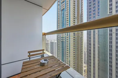 a wooden bench on a balcony with tall buildings at Luxury 1BD in Elite Residence, Dubai Marina in Dubai