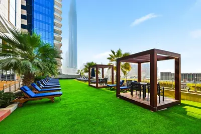a row of blue lounge chairs on a green lawn at Luxury 1BD in Elite Residence, Dubai Marina in Dubai