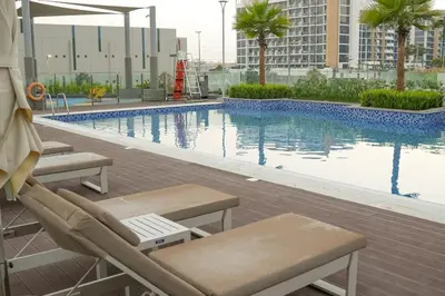 a swimming pool with lounge chairs and a building at Stunning - Cozy Studio - Azizi Riviera in Dubai