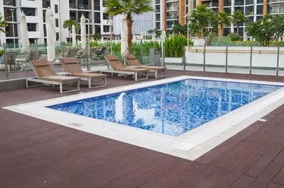 a swimming pool with lounge chairs next to a building at Stunning - Cozy Studio - Azizi Riviera in Dubai