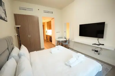a living room with a white couch and a flat screen tv at Stunning - Cozy Studio - Azizi Riviera in Dubai