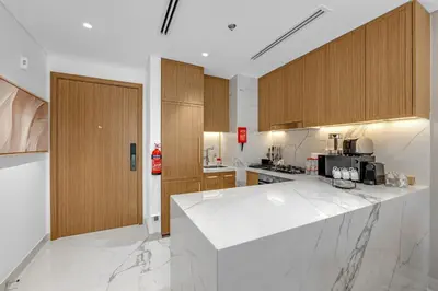 a kitchen with white counter tops and wooden cabinets at Charming 2BR Getaway at Azizi Riviera, MBR City in Dubai