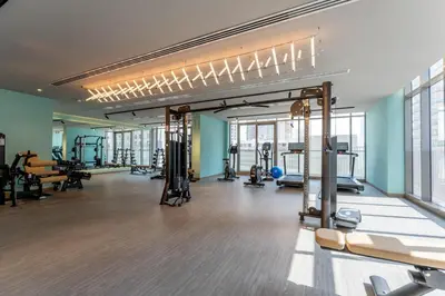 a gym with several treadmills and machines in a room at 1BDR near Circle Mall with Sauna, Jaccuzzi and Gym in Dubai