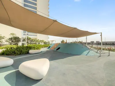 a skate park with a ramp and chairs and a umbrella at ALiving Elegant 1BR I Golf Gate, DAMAC Hills in Dubai
