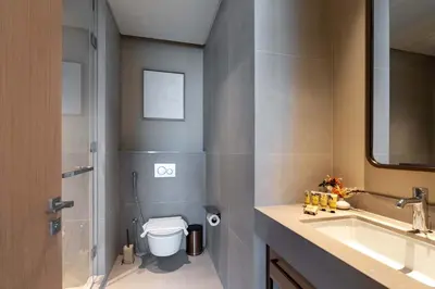 a bathroom with a toilet and a sink and a mirror at PVH - Burj Khalifa View 2BR - Vida Dubai Mall in Dubai