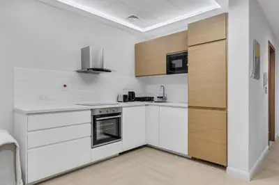 a white kitchen with wooden cabinets and appliances at Elegant 1BR with Balcony in Dubai Marina by EE Holiday Homes in Dubai