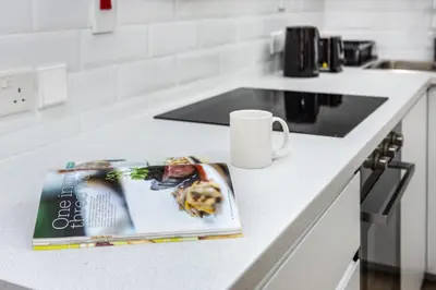 a magazine sitting on a kitchen counter with a coffee mug at Elegant 1BR with Balcony in Dubai Marina by EE Holiday Homes in Dubai