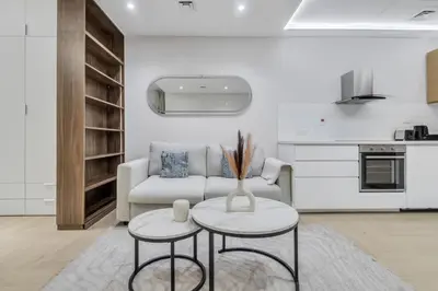 a white living room with a couch and two tables at Elegant 1BR with Balcony in Dubai Marina by EE Holiday Homes in Dubai