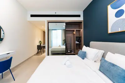 a bedroom with a white bed and a blue wall at HAVN - Modern Studio in Dusk, Al Barsha in Dubai