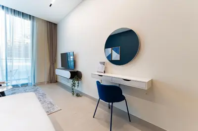 a white room with a mirror and a blue chair at HAVN - Modern Studio in Dusk, Al Barsha in Dubai