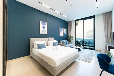 a bedroom with a bed and a blue wall at HAVN - Modern Studio in Dusk, Al Barsha in Dubai