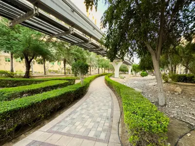 a walkway in a park with trees and a building at Spacious 1BR with Terrace l Near Palm Jumeirah Mall in Dubai