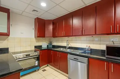 a kitchen with wooden cabinets and a sink and a dishwasher at Luxe 3 Bedroom Apartment with Maid Room, Dubai Eye and Sea View in Dubai