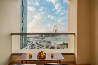 a table with a bowl of fruit in front of a window at Luxe 3 Bedroom Apartment with Maid Room, Dubai Eye and Sea View in Dubai
