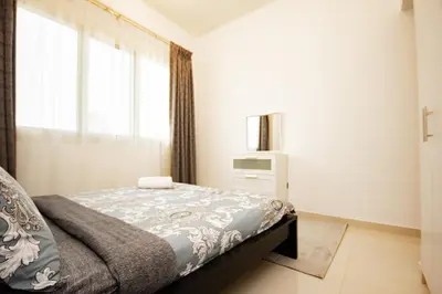 a bedroom with a bed and a tv and a window at Dezire Premium Fully Furnished 1 BHK Apartment in Dubai