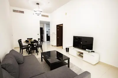 a living room with a couch and a tv and a table at Dezire Premium Fully Furnished 1 BHK Apartment in Dubai