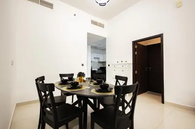 a dining room with a black table and chairs at Dezire Premium Fully Furnished 1 BHK Apartment in Dubai