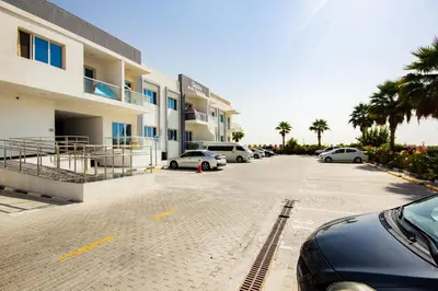 a parking lot with cars parked in front of a building at Dezire Premium Fully Furnished 1 BHK Apartment in Dubai
