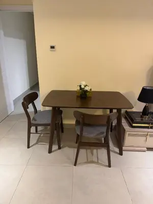 a wooden table with two chairs and a vase of flowers on it at Joyful Journeys Marina Arcade Private Room for 2 - Shared Kitchen in Dubai