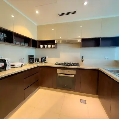 a kitchen with brown cabinets and a stove top oven at Spacious Luxury Apartment Stunning Creek Views Family Friendly in Dubai