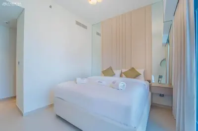 a white bedroom with a large bed and a mirror at Burj Khalifa - Fountain View - Astonishing Home in Dubai
