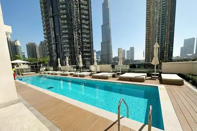 a swimming pool with chaise lounges and a city at Burj Khalifa - Fountain View - Astonishing Home in Dubai