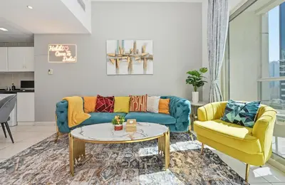 a living room with a blue couch and yellow chairs at Vibrant 1 Bedroom Marina View - Stylish and Bright Stay in Dubai