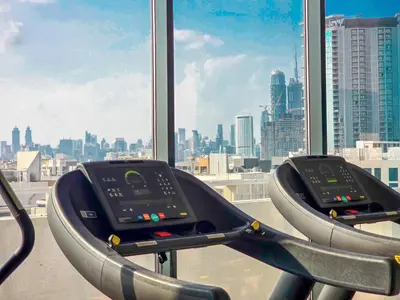 a gym with a view of a city skyline at EasyGo - Elegant 1-Bedroom Apartment with Balcony in Dubai