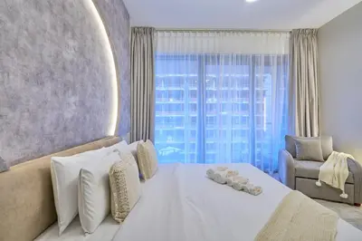 a bedroom with a white bed and a chair and a window at Luxury 1BR Downtown Modern Urban Stay in Dubai