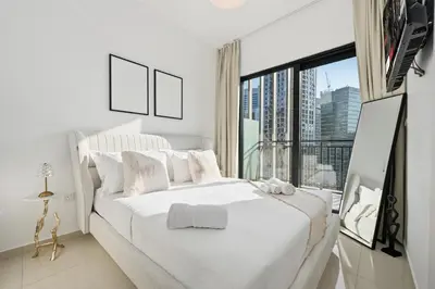 a white bedroom with a large white bed and a window at Zada 1BR High Floor - Stunning View 1min Downtown and 2min to Metro in Dubai