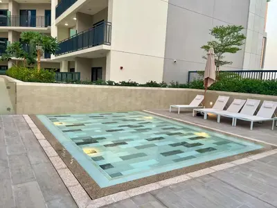 a swimming pool with chairs and an umbrella next to a building at Zada 1BR High Floor - Stunning View 1min Downtown and 2min to Metro in Dubai
